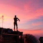 Majestic statue silhouettes against a vibrant sunset sky in Đà Nẵng, Vietnam.