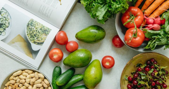 An appetizing display of fresh fruits and vegetables with a cookbook, perfect for healthy recipes.